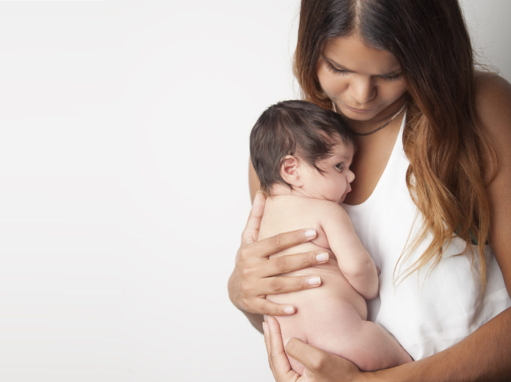 Australian mother holding newborn baby girl on white background